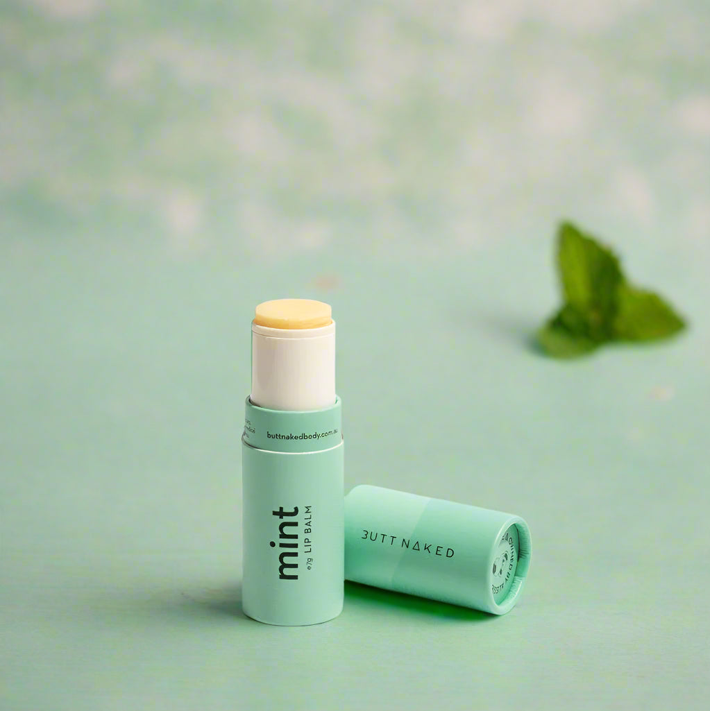 A stick of mint lip balm with the cap removed, prominently displaying the product against a light background.