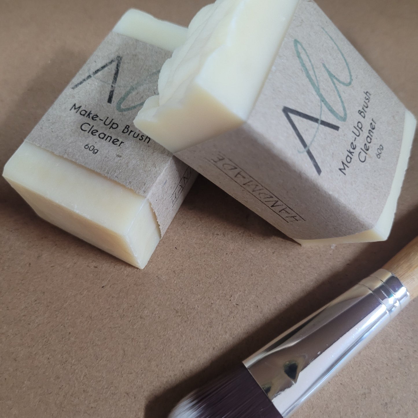 Two makeup sponges and a brush on a brown surface