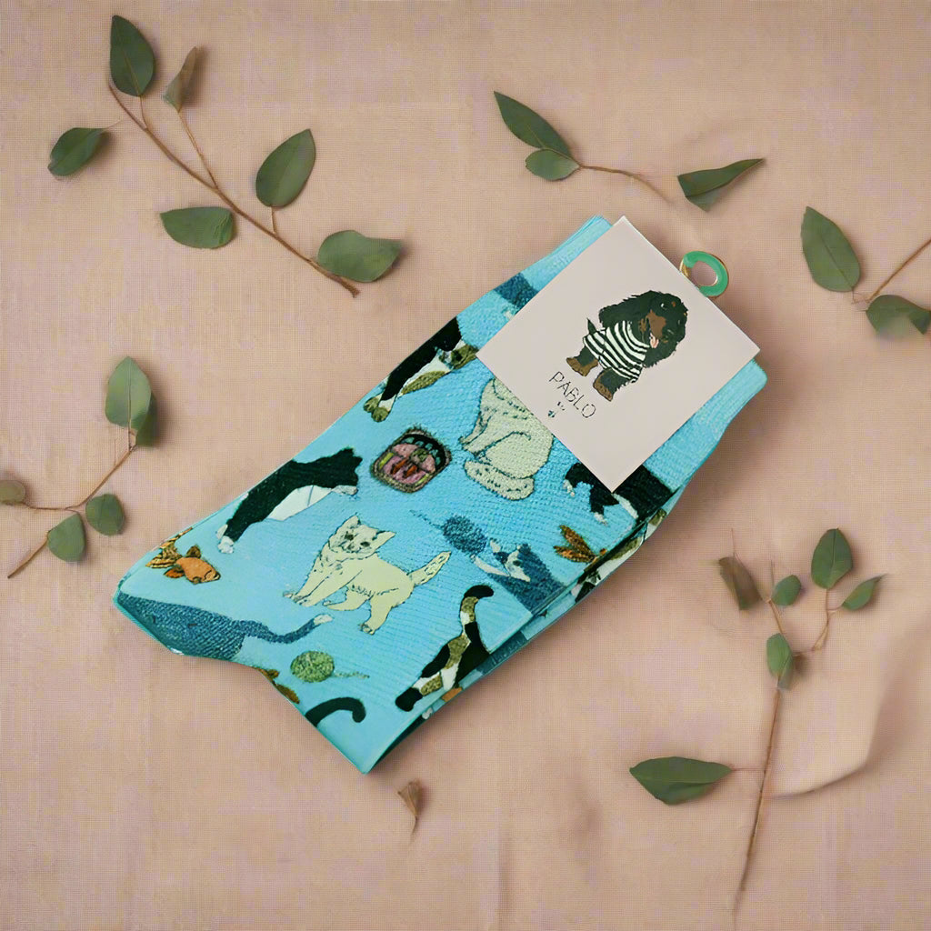 this is an image of blue cat socks on a pink background with leaves