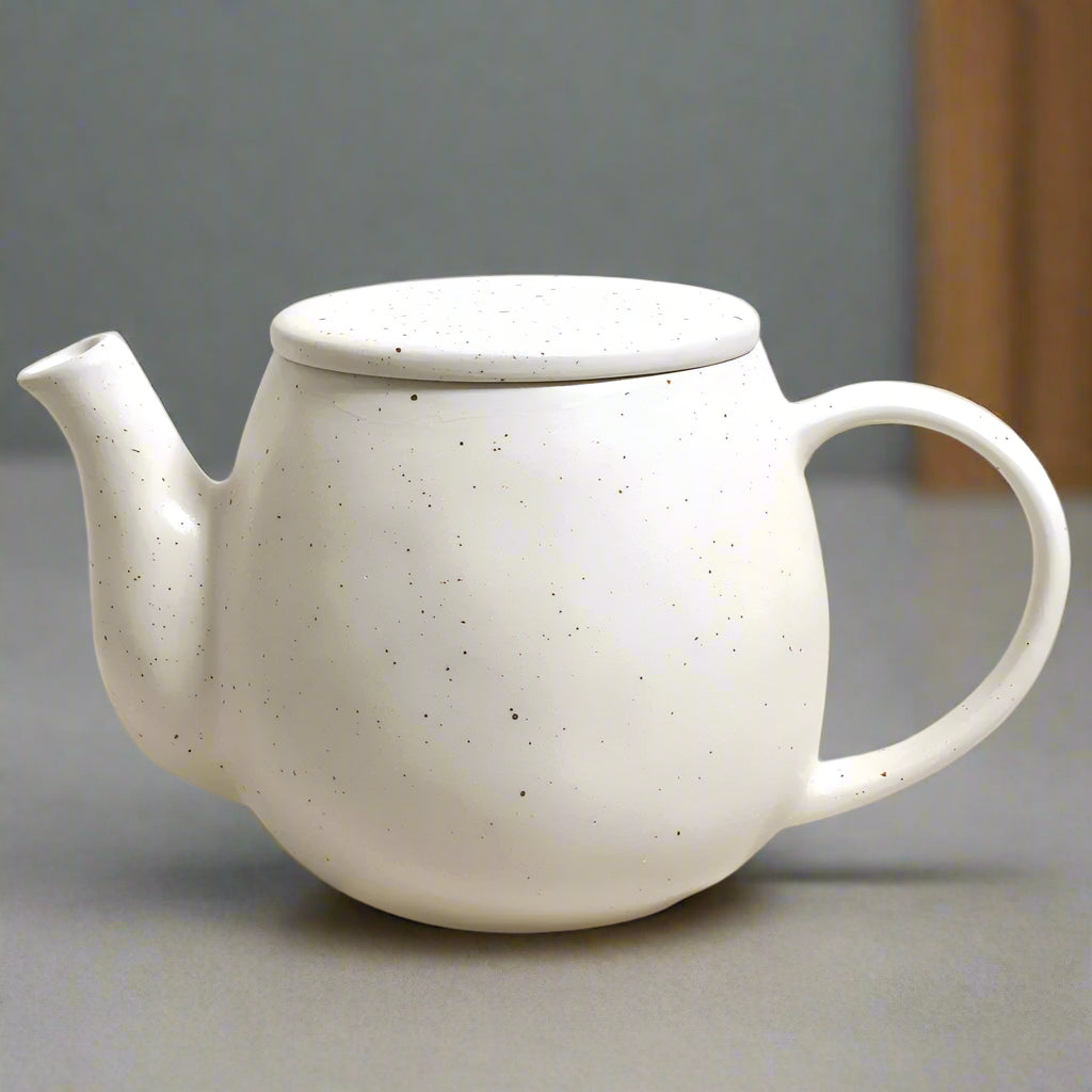 White ceramic teapot with speckled texture on a white background