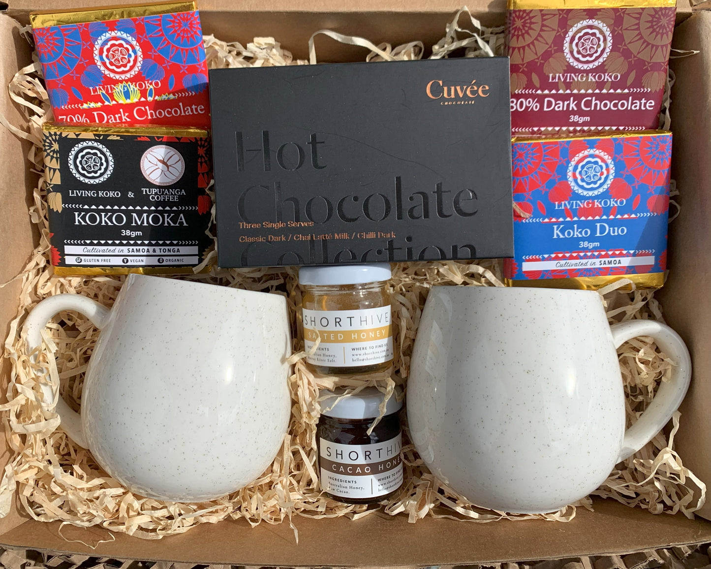 Gift set with white mugs, hot chocolate bars, and chocolate truffles in a box.