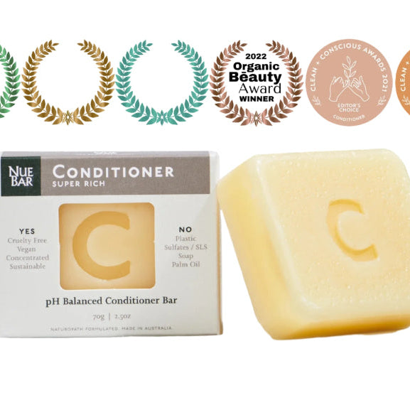 A solid conditioner bar labeled 'NueBar Conditioner Super Rich' alongside its packaging which states 'pH balanced'. There are also several award badges displayed.