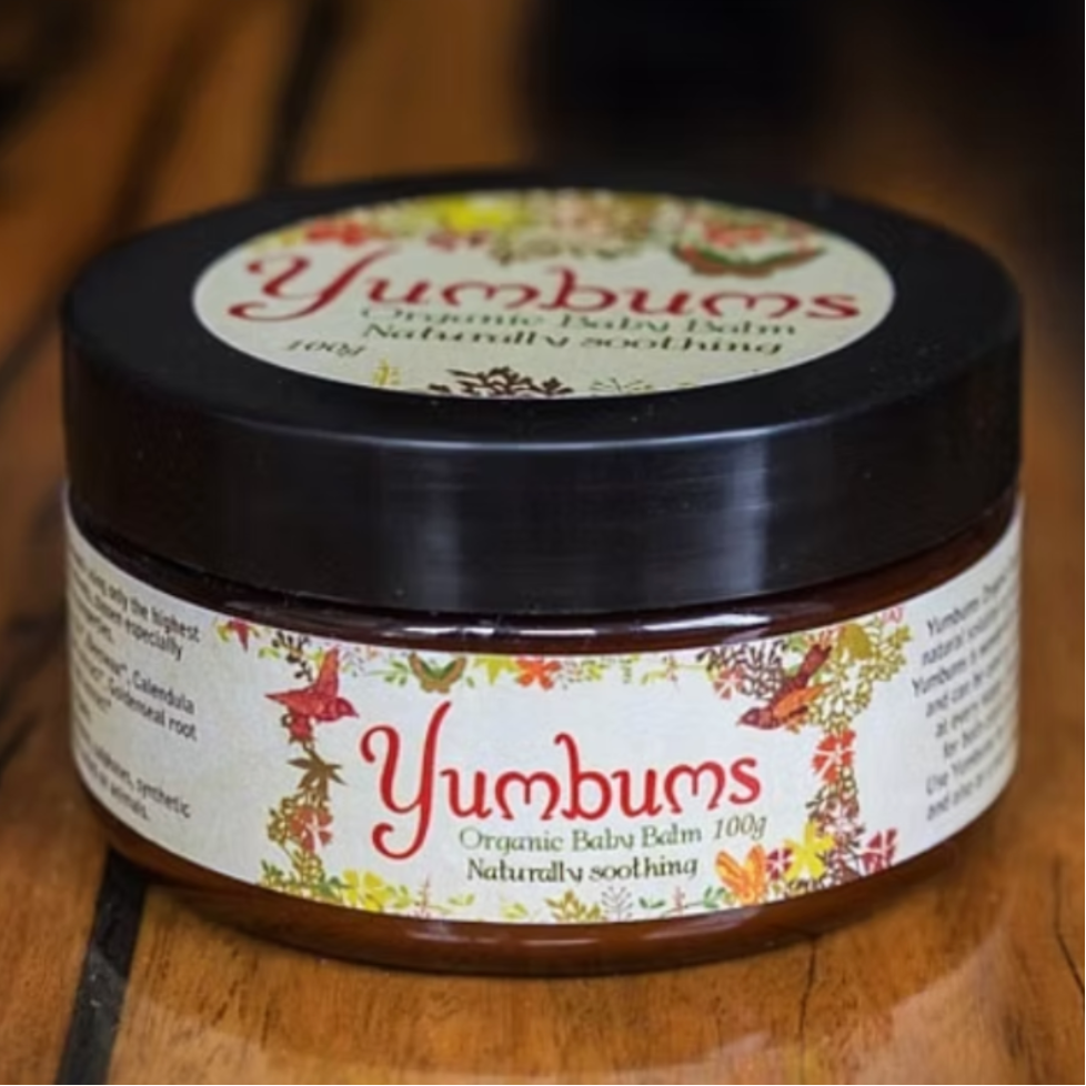 Yumbums organic baby balm jar on a wooden surface