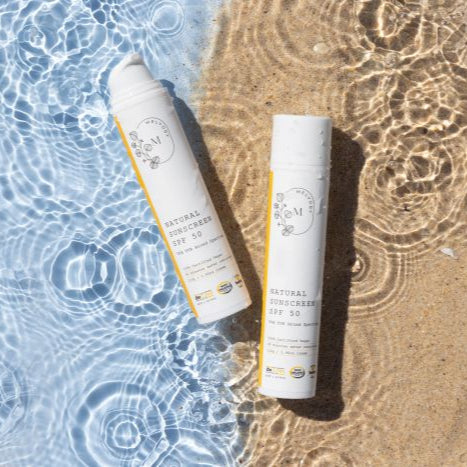 image of 2 sunscreen bottles in water and sand