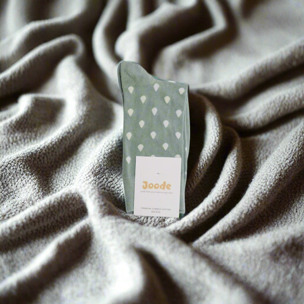 A pair of light green socks with a raindrop pattern, displayed with the brand tag visible.