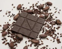 Chocolate bar surrounded by chocolate pieces on a light background