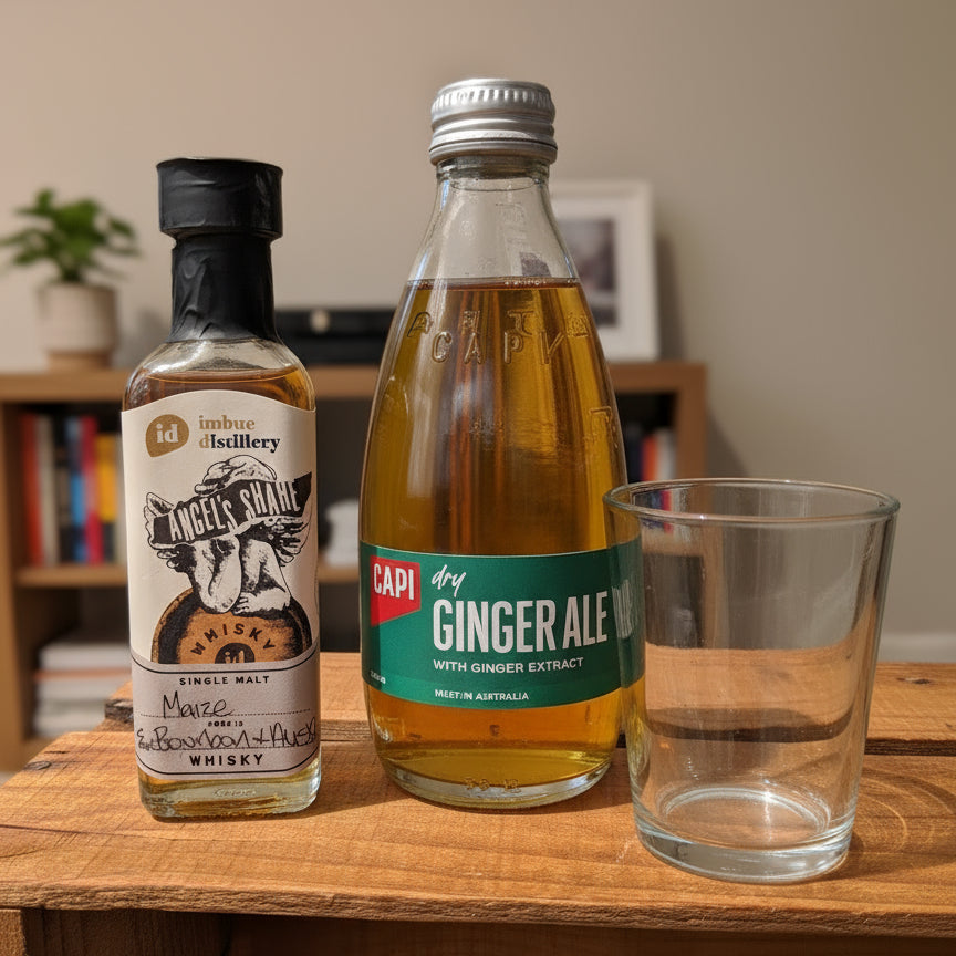 Two bottles of alcohol and ginger ale with a glass on a wooden surface.