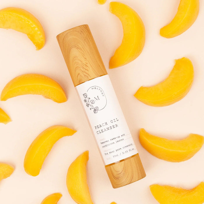 this is an image of a peach oil cleanser against a background of peach slices