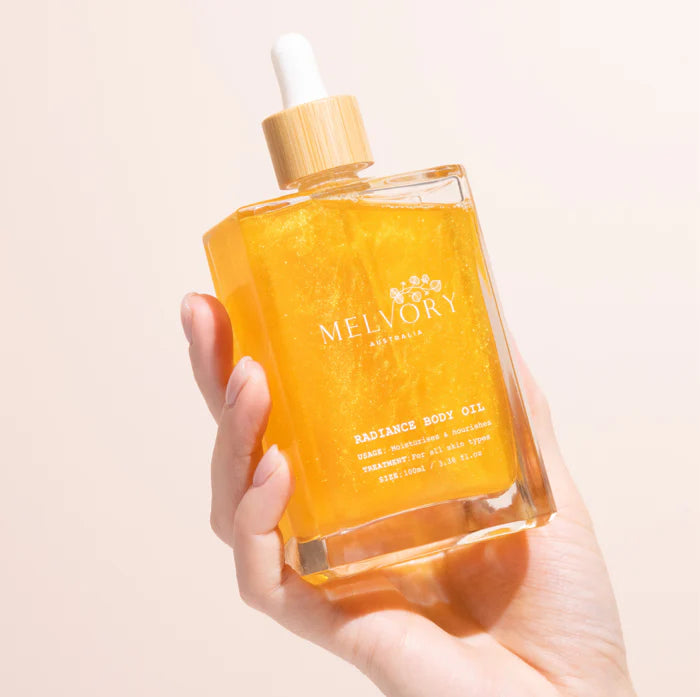 this is an image of a lady holding a gold shimmer luxurious looking body oil