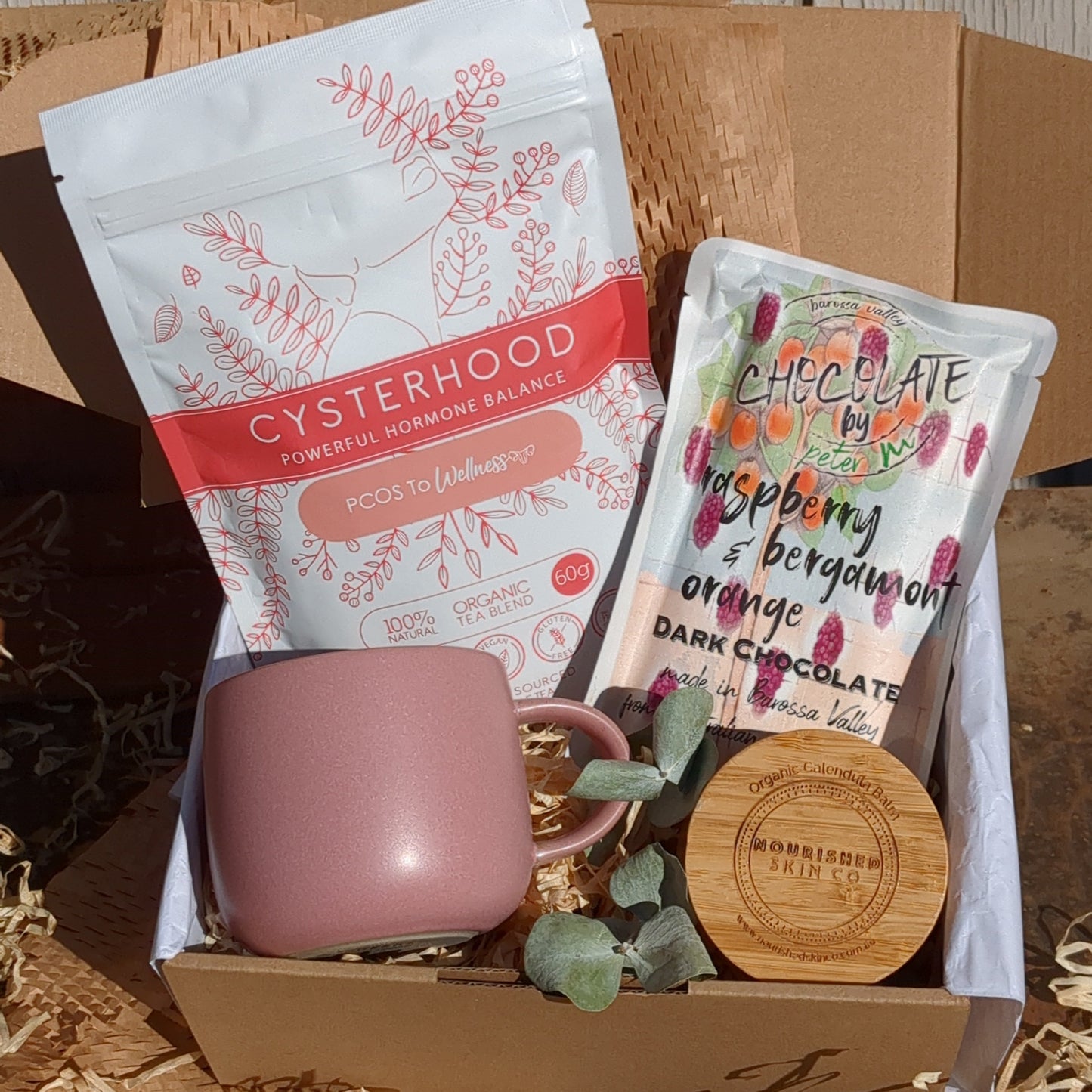Pink mug and packets in a box on a wooden surface