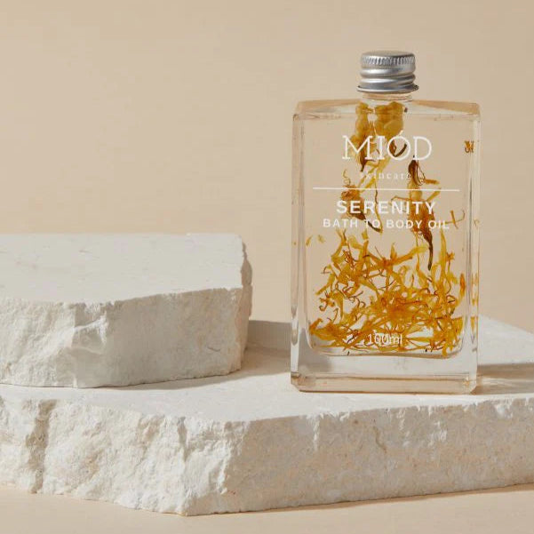 Bottle of 'Serenity' bath oil with a decorative label on a beige background