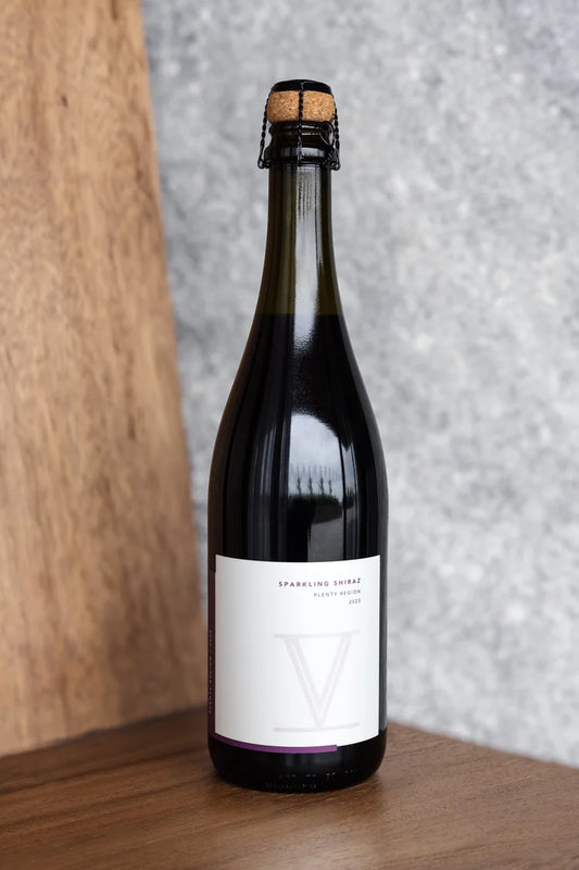 Bottle of sparkling wine with a cork on a wooden surface and gray textured background