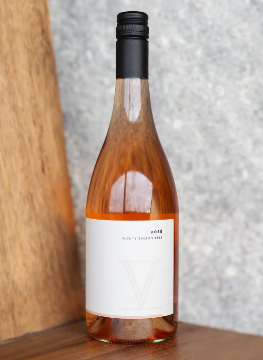 Bottle of rose wine with a white label on a wooden surface.