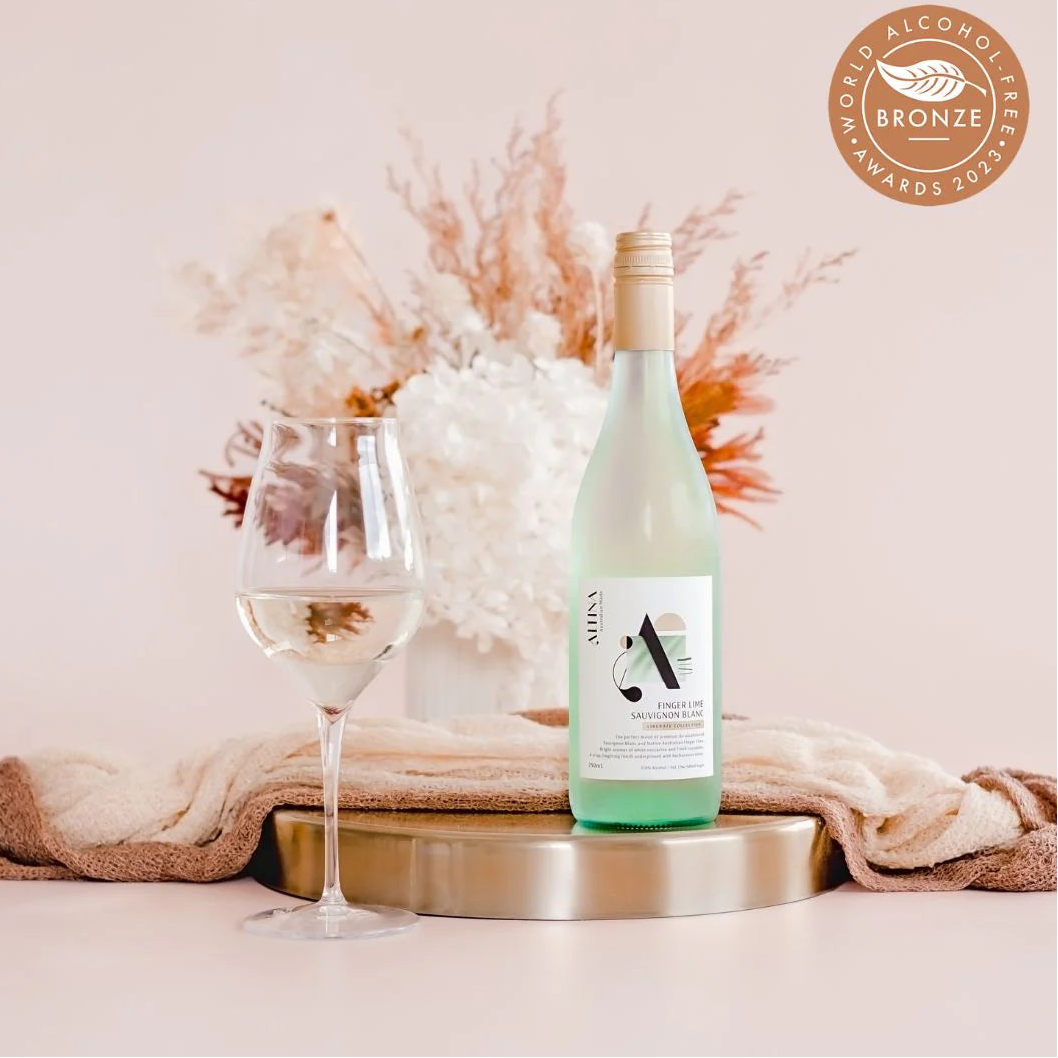 Bottle of alcohol-free wine with a glass on a decorative surface, featuring a bronze award badge.