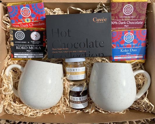 Gift set with white mugs, hot chocolate bars, and chocolate truffles in a box.