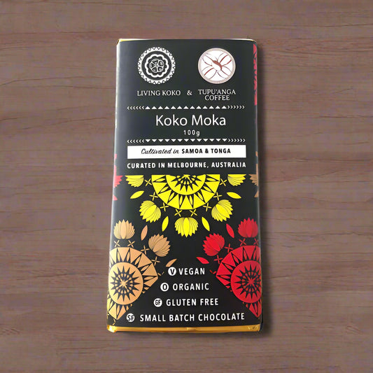 A chocolate bar packaging with a colorful design featuring geometric shapes in red, black, and yellow. The text indicates the product is 'Koko Moka', 100g, made with organic dark chocolate and tupu'anga coffee, vegan, organic, and gluten-free.