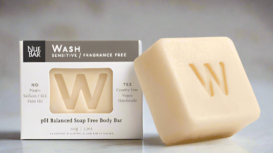 A solid body wash bar next to its packaging, which indicates it is pH balanced, soap-free, and suitable for sensitive skin.