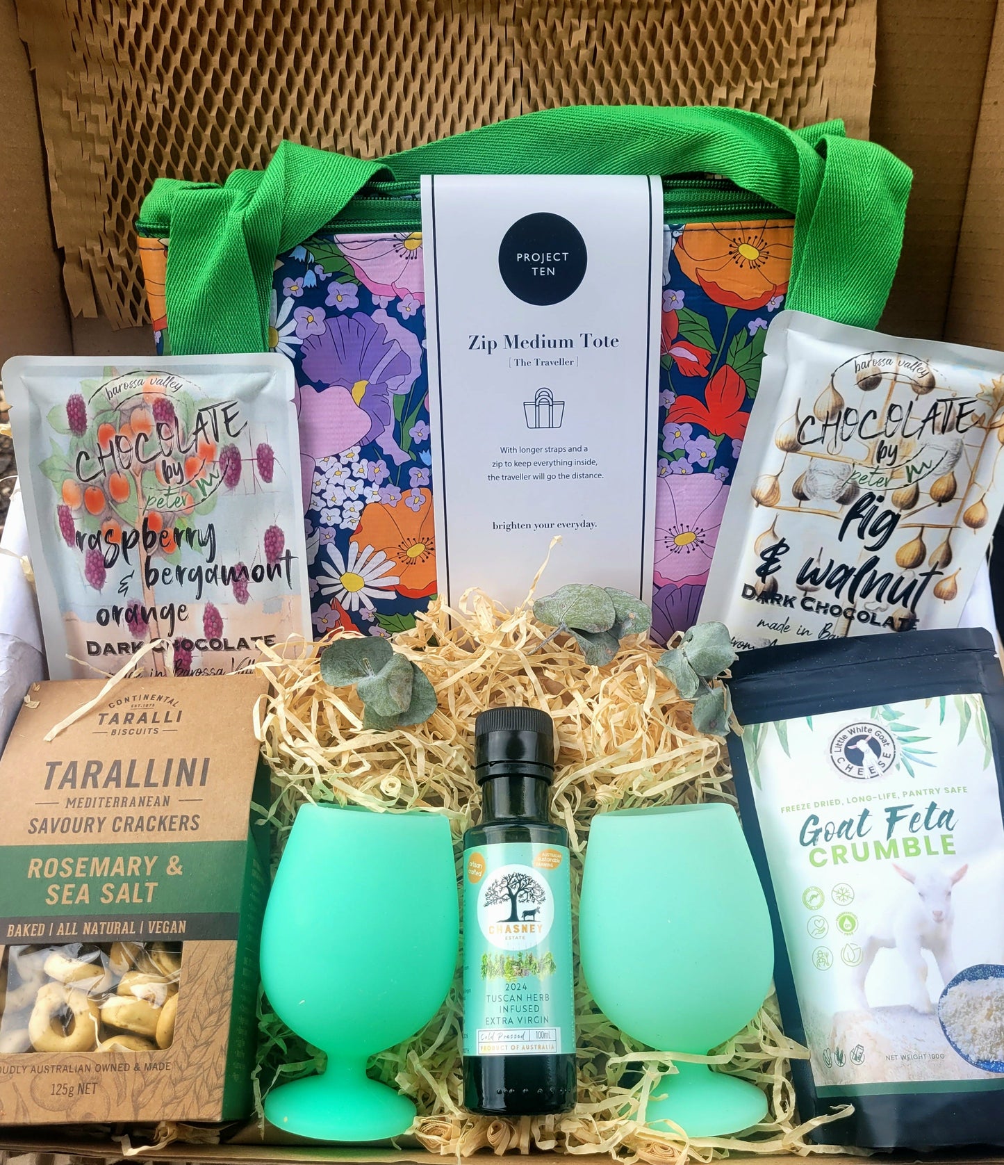 Gift basket with green silicone glasses, chocolate, feta and savoury biscuits.