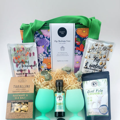 Gift basket with green silicone glasses, chocolate, feta and savoury biscuits.