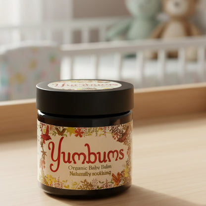 Yumbums Organic Baby Balm jar on a wooden surface with a natural background