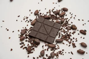 Chocolate bar surrounded by chocolate pieces on a light background