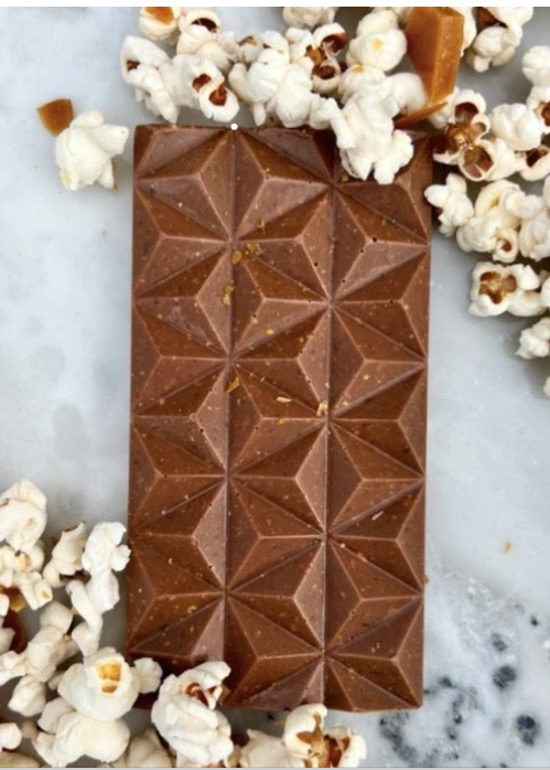 Chocolate bar with geometric pattern on a marble surface with popcorn