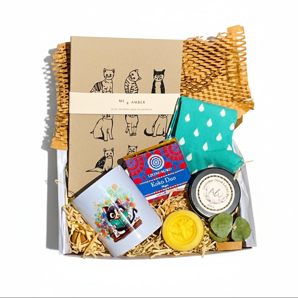 Collection of items including a notebook, pouch, soap, and other products with branding on a textured surface.