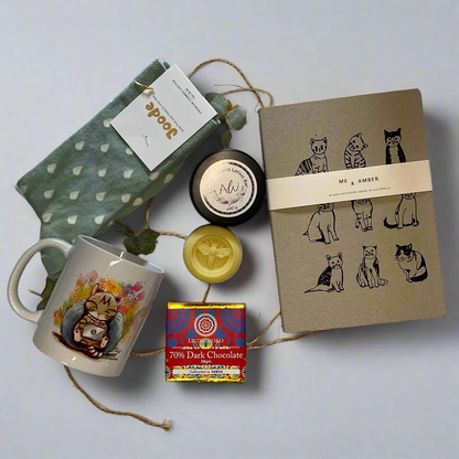 Collection of items including a mug, notebook, and candles on a white surface
