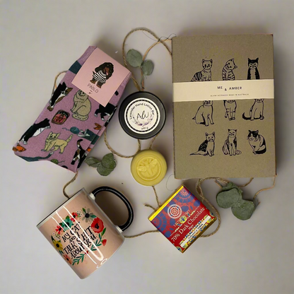 Collection of stationery items including a mug, notebook, and pouches on a white surface.