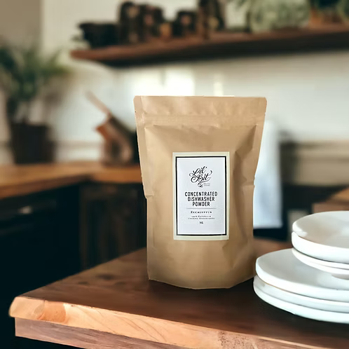 Kraft paper bag of concentrated dishwasher powder on a wooden surface with a blurred kitchen background.